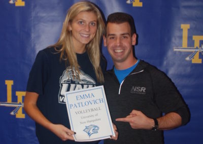 A man and woman participating in a college signing day event, posing for a picture while holding a plaque.
