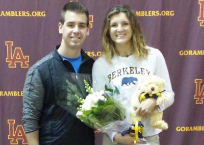 A man and woman celebrating college signing day with flowers and a teddy bear.