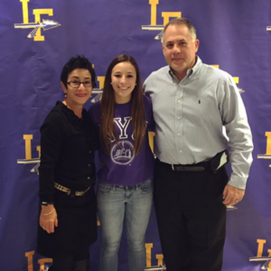 A man and a woman celebrating college signing day in front of a banner.