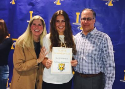 A man and a woman are posing for a picture with a certificate on college signing day.