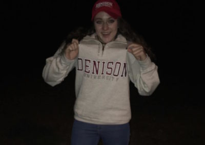 A girl, excited for college signing day, is wearing a Denison sweatshirt and a hat.