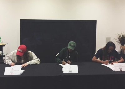 Three women participating in college signing day at a table.