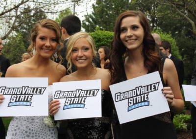 Three girls participate in a college signing day event at Grand Valley State University, proudly holding signs that say "Grand Valley State.
