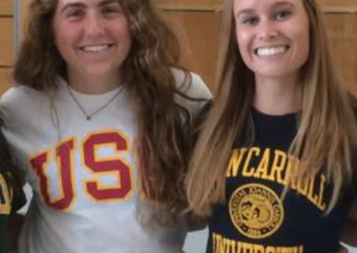 Four women are posing for a photo on college signing day in a gym.