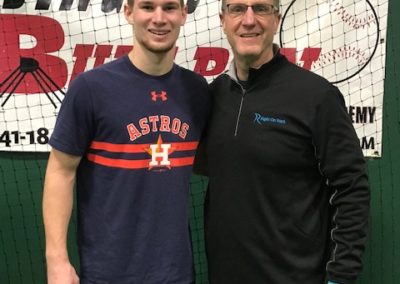 Two men standing next to each other in a batting cage on college signing day.