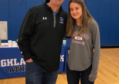 A man and a woman celebrating their college signing day as they stand next to each other in a gym.