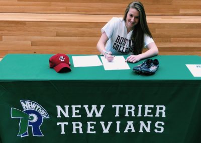 A recruiting girl signing her letter of intent at a table.