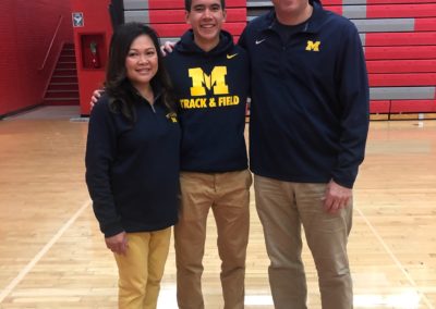Three people celebrating college signing day in a gym.