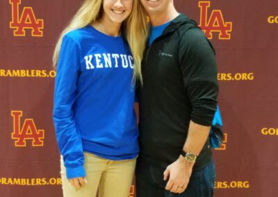 A man and woman participating in college signing day, posing for a picture in front of a Kentucky banner.