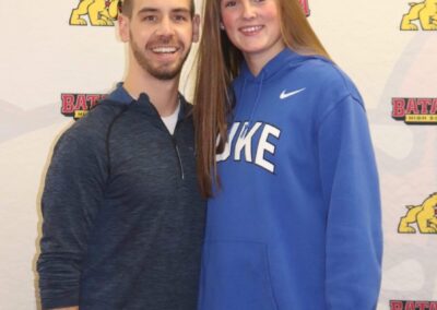 A man and woman standing next to each other at a college signing day.