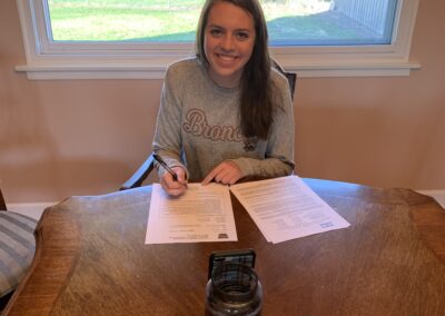 A girl celebrating college signing day with papers and a cup of coffee.