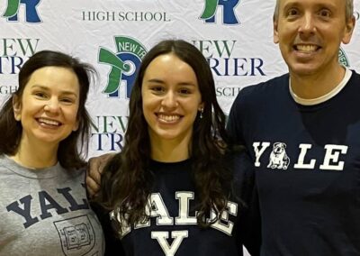 A group of people celebrating college signing day by posing for a picture in front of a banner.