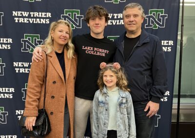 A family posing for a picture in front of the trevians logo.