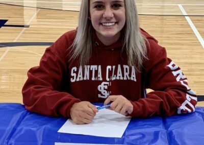A girl sitting at the table signing her letter of intent.