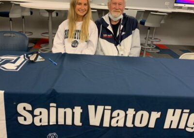 Two people sitting at a table with a sign