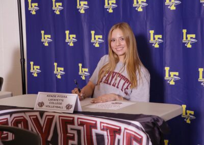 A girl sitting at a table signing her college letter of intent.