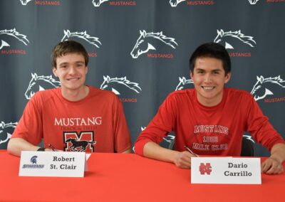 Two men sitting at a table with signs on them.